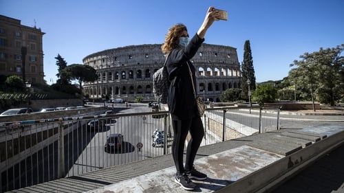 A woman takes a selfie wearing a protective mask in front of the Colosseum in Rome