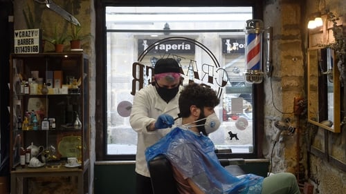 Barber David Cores cuts his first client's hair after reopening his shop in Pontevedra in Spain