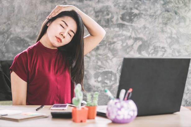 female business woman stretching neck to relax muscle of shoulder sitting at office desk