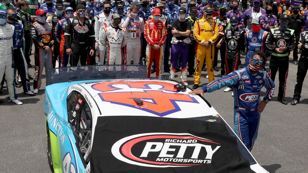 Bubba Wallace stands by his car after NASCAR drivers pushed him to the front of the grid