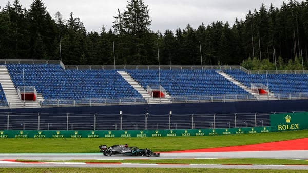 Lewis Hamilton steers his car past empty stands during the first practice session
