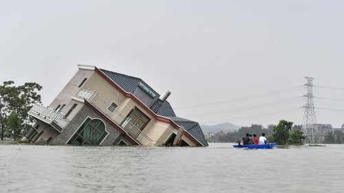 Residents ride a boat past a damaged house near the Poyang Lake in China's central Jiangxi province