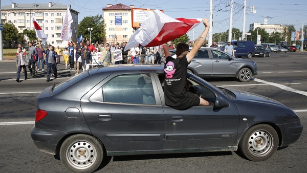An opposition supporter waves an old Belarusian national flag from a car window in Minsk