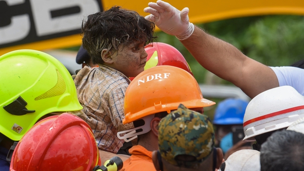 Rescue workers carry the four-year-old boy after he is pulled from the rubble of a collapsed building in Mahad