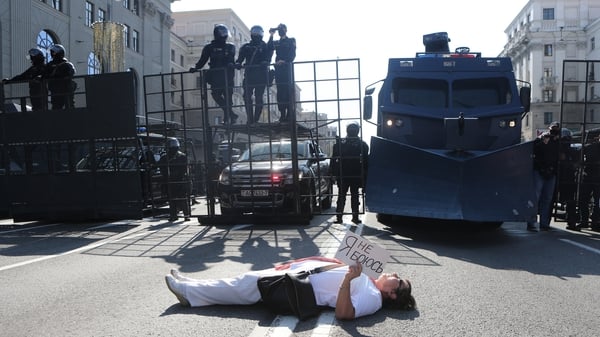 A woman lies down in front of police in Minsk, Belarus, holding a sign that says 'I am not afraid'