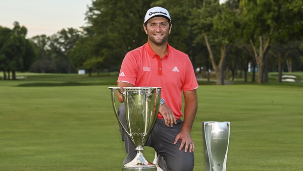 Jon Rahm smiles with the tournament trophy and the Western Golf Association (WGA) Open J.K. Wadley Championship Cup trophy
