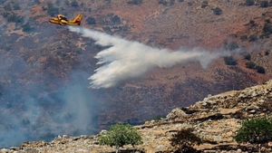 A firefighting plane drops water to extinguish the flames in Greece
