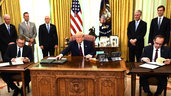 Donald Trump watches as Kosovar Prime Minister Avdullah Hoti (R) and Serbian President Aleksandar Vucic sign an economic agreement