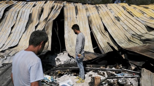 People view the remains and debris after a fire destroyed the Moria refugee camp