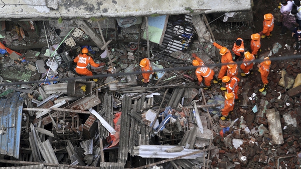 Rescue workers search for survivors in the rubble of a collapsed three-storey residential building in Bhiwandi