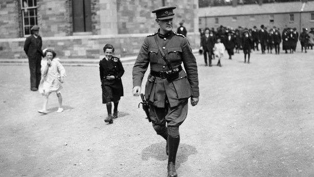 Michael COllins strides across a courtyard in military uniform