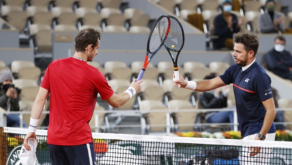 Stan Wawrinka of Switzerland (R) knocks racquets with Andy Murray of Great Britain as part of Covid-19 precautions following victory