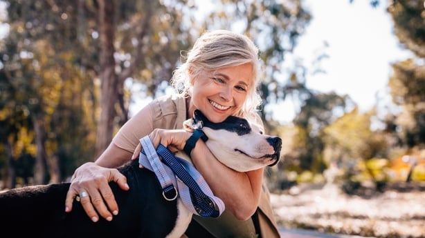 Affectionate mature woman embracing pet dog in nature