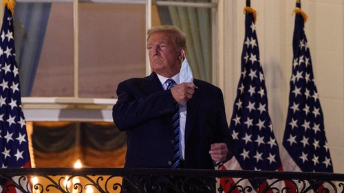 Donald Trump removing his face mask on the balcony of the White House