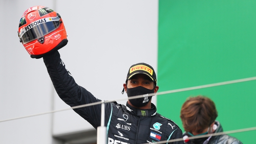 Lewis Hamilton celebrates on the podium after being presented with one of Michael Schumacher's helmets
