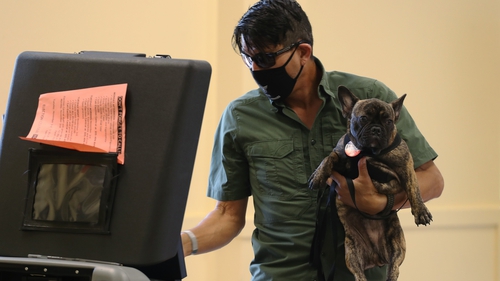 Florida voter Auggie Mejia holding his dog, Baby, casts his ballot in Miami