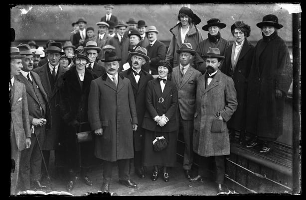 The photo shows four of the Anglo-Irish Treaty signatories surrounded by supporters, Holyhead, Wales 6 December 1921. From left to right (after the woman in the foreground on the left) you can see Arthur Griffith, Eamon J Duggan, Robert Barton and George Gavan-Duffy.