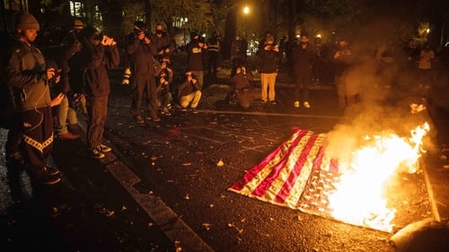 A US flag burns during a protest in front of a federal courthouse in Portland