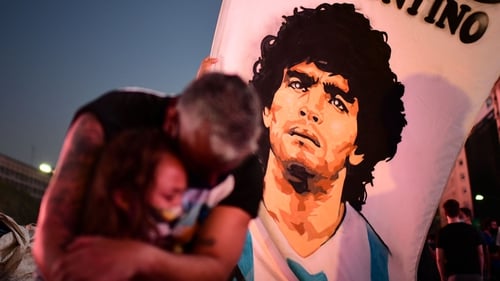 A father and daughter mourn as they gather by the Obelisk in Buenos Aires to pay homage to Diego Maradona