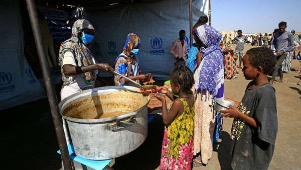 Ethiopian refugees who have fled the Tigray conflict receive food at a transit centre in Sudan's border town of Hamdayit on 27 November
