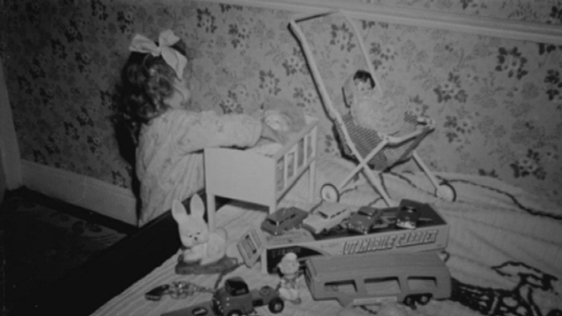 Little girl playing with toys on Christmas morning (1963)