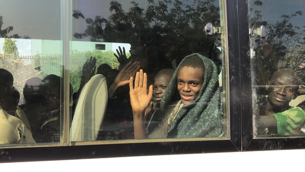 A boy waves from a bus full of children following their release