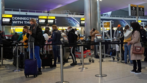 Customers queue at a check-in desk in the departures hall at Terminal 2 of Heathrow Airport in London today