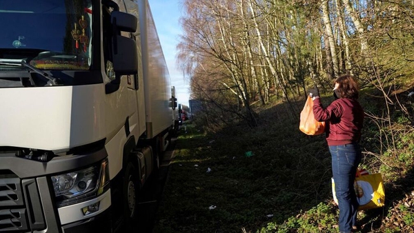 A local resident distributes provisions to freight lorry drivers as they remain queued up on the M20 motorway