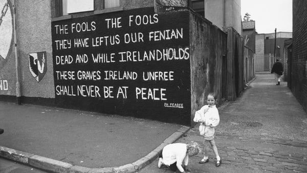 Two girls pictured near a mural on the Falls Road in Belfast c1990