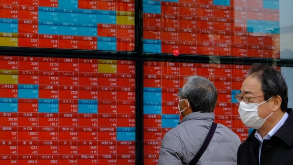 People look at an electronic board displaying the Nikkei 225 index on the Tokyo Stock Exchange