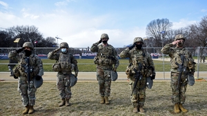 Members of the National Guard salute as they stand near the US Capitol while the National Anthem is sung