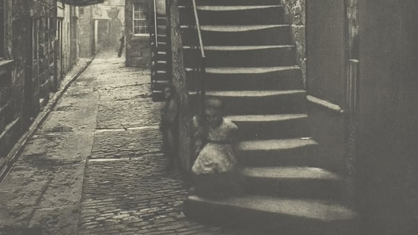 A child sits on the steps of a tenement building in Glasgow in the mid 19th century.
