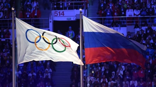 The Olympic flag (L) and the Russian flag flutter during the Closing Ceremony of the Sochi Winter Olympics