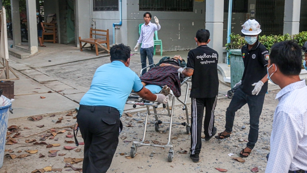 A wounded man on a stretcher after police and military opened fire on protesters in Mandalay yesterday