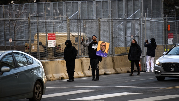 A man carries a portrait of George Floyd outside the court