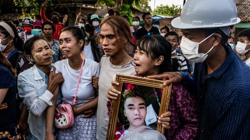 The family of a 25-year-old killed during protests in Yangong hold his photo at his funeral