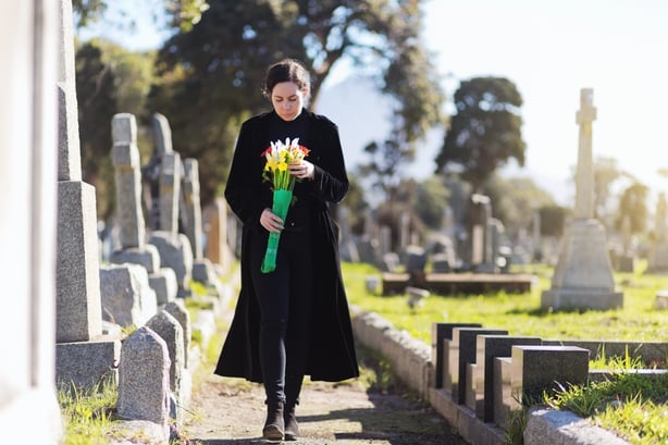 woman bringing flowers to a grave