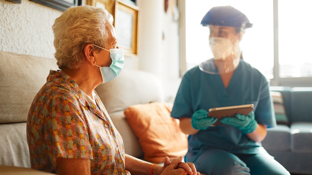 elderly woman speaking with health care in PPE
