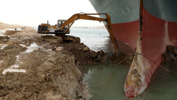 A digger extracts sand from around the Ever Given vessel which ran aground diagonally across the Suez Canal on Tuesday morning