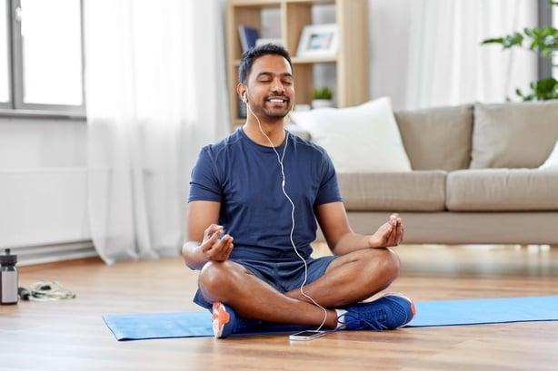 man meditating in lotus pose at home