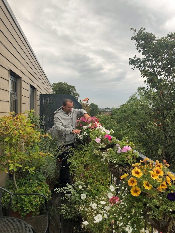 Garden Organic's Chris Collins looks after the hanging plants on his balcony (Garden Organic/PA)