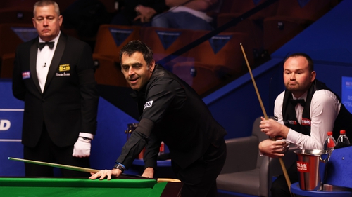 Ronnie O'Sullivan reacts after playing a shot as Mark Joyce (R) looks on