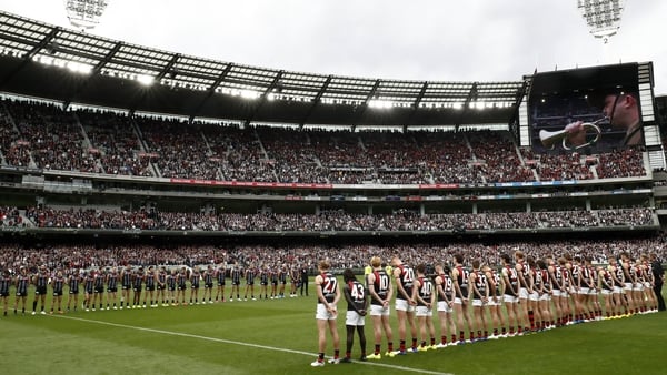 Essendon and Collingwood players line up in front of full stands at the Melbourne Cricket Ground