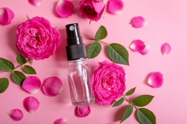 Rose water spray surrounded by roses (Alamy/PA)