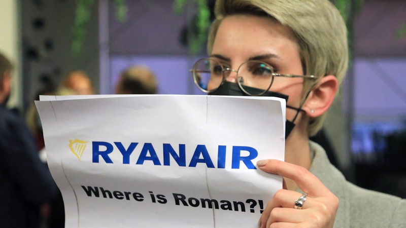 A woman stands with a poster reading 'Where is Roman (Protasevich)?' in the arrival area as passengers disembark from the diverted flight after arriving in Vilnius