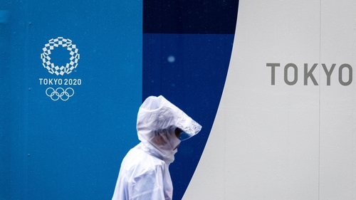 A pedestrian walks past a 2020 Olympic and Paralympic Games logo on a decoration board in Tokyo