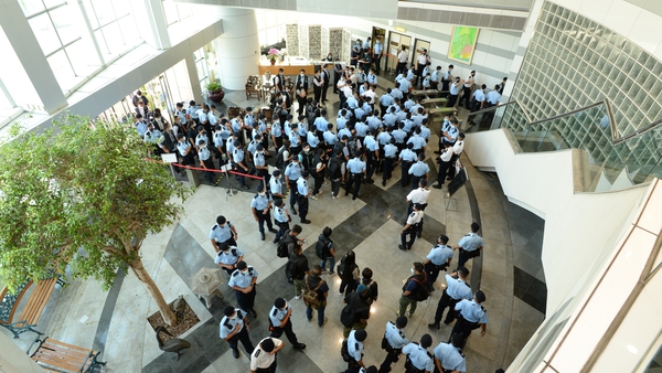 A photo made available by Apple Daily shows police officers arriving at the office of Next Media