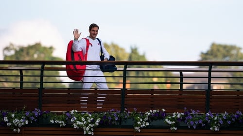 Roger Federer waves to fans as he walks across the players bridge at Wimbledon