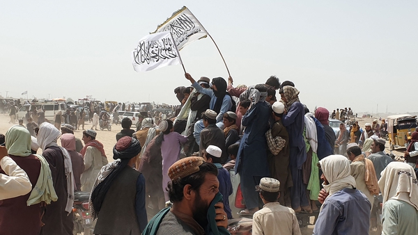 People wave Taliban flags as they drive through the Pakistani border town of Chaman after the Taliban claimed they had captured the Afghan side of the border crossing of Spin Boldak