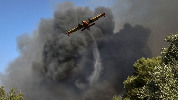 A plane drops water on flames around the town of Labiri, near Patras in Greece